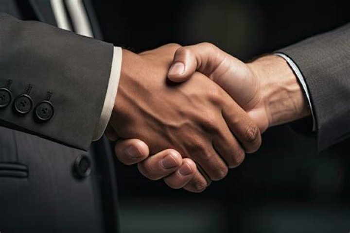 Two men shaking hands holding paperwork